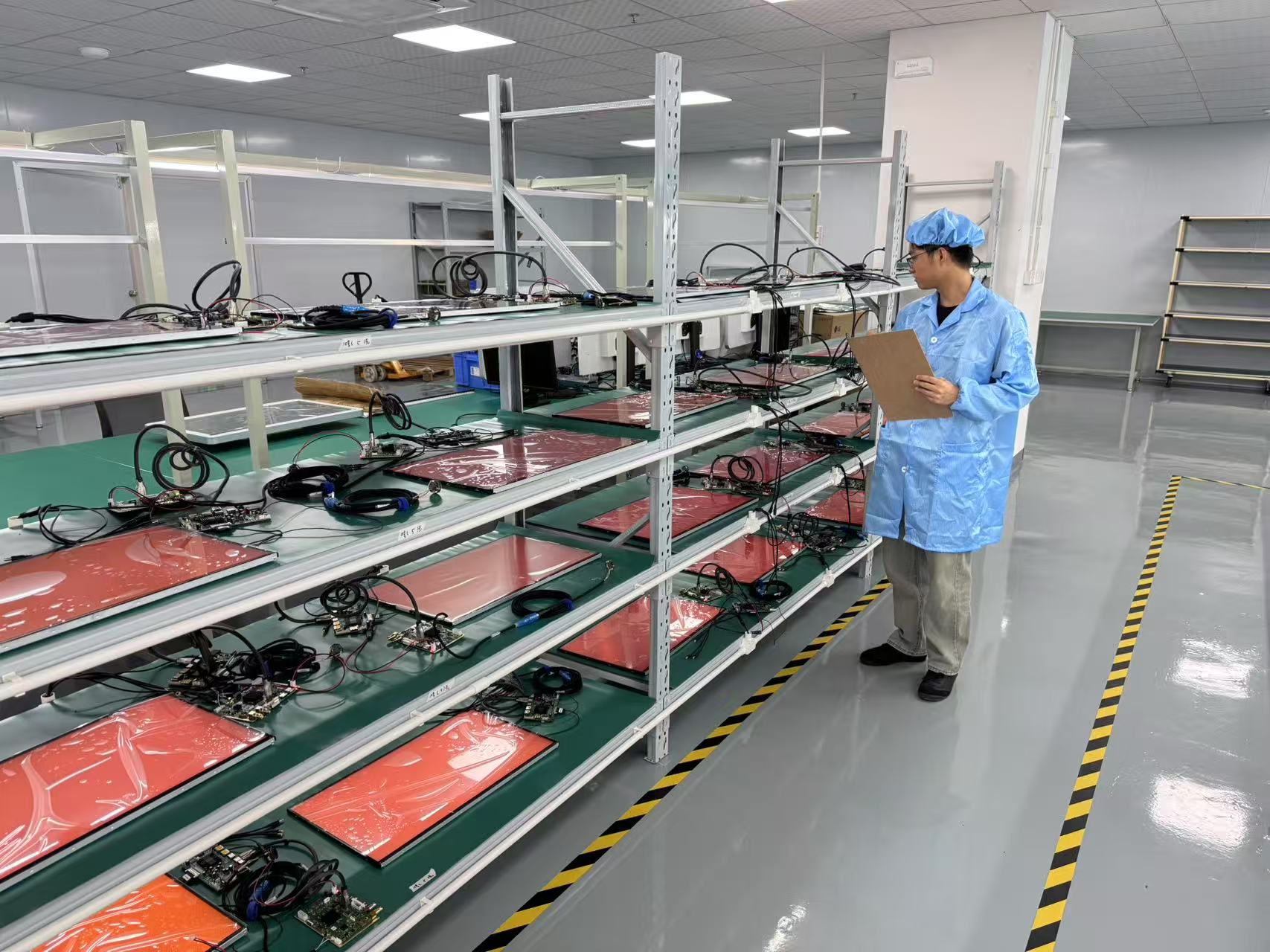 Technician inspecting electronic devices connected on multi-tier testing racks